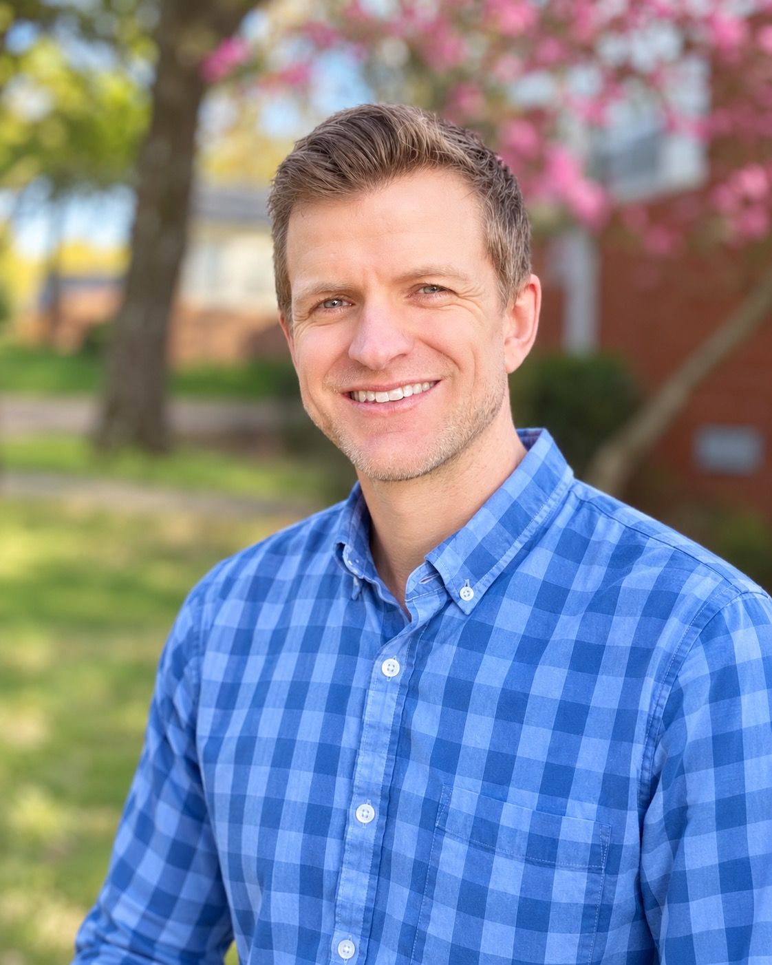 Josh Cesana, smiling, outdoors in a blue checked shirt